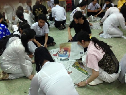 新聞紙を広げる生徒たちの写真