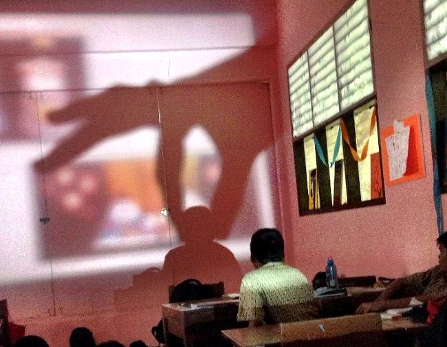 プロジェクターに大きな手の影を映して楽しむ生徒の写真
