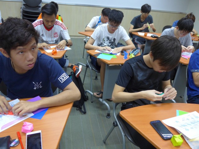 渡邊さんの説明を聞きながら折り紙を折る生徒の写真