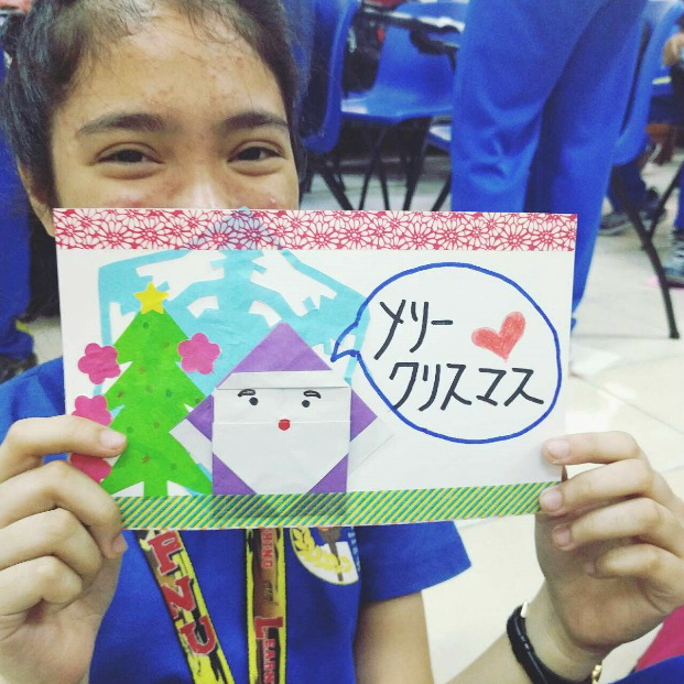 手作りクリスマスカードを持った生徒の写真