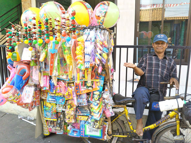 自転車の荷台に大量のおもちゃを積んでいるおもちゃ売りの写真