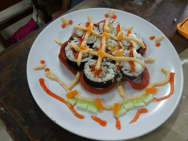 赤や白のソースがかかった巻き寿司の写真