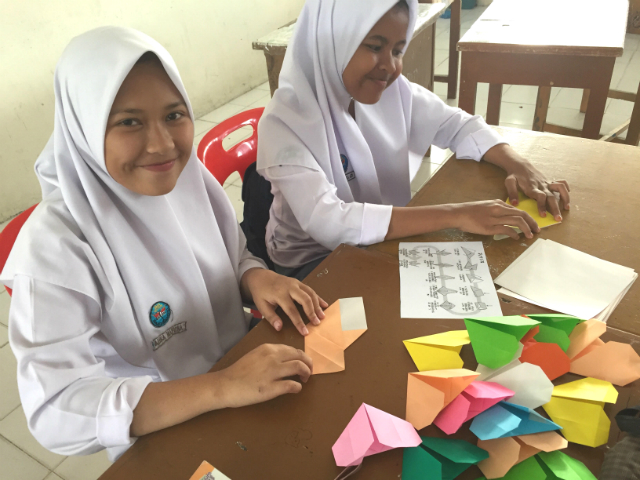 折り紙を折る女子生徒たちの写真