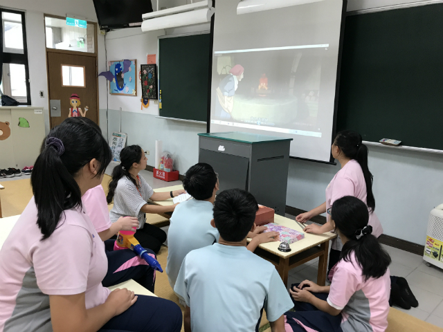 プロジェクターでアニメ映画を映して鑑賞する生徒たちの写真