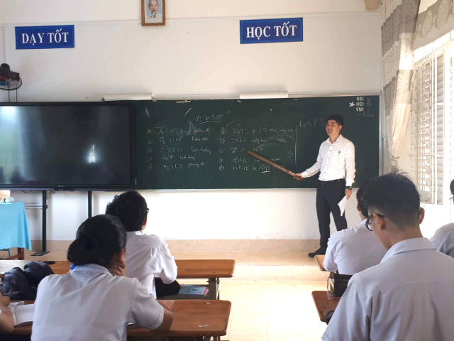 黒板を指しながら教える新山さんの写真