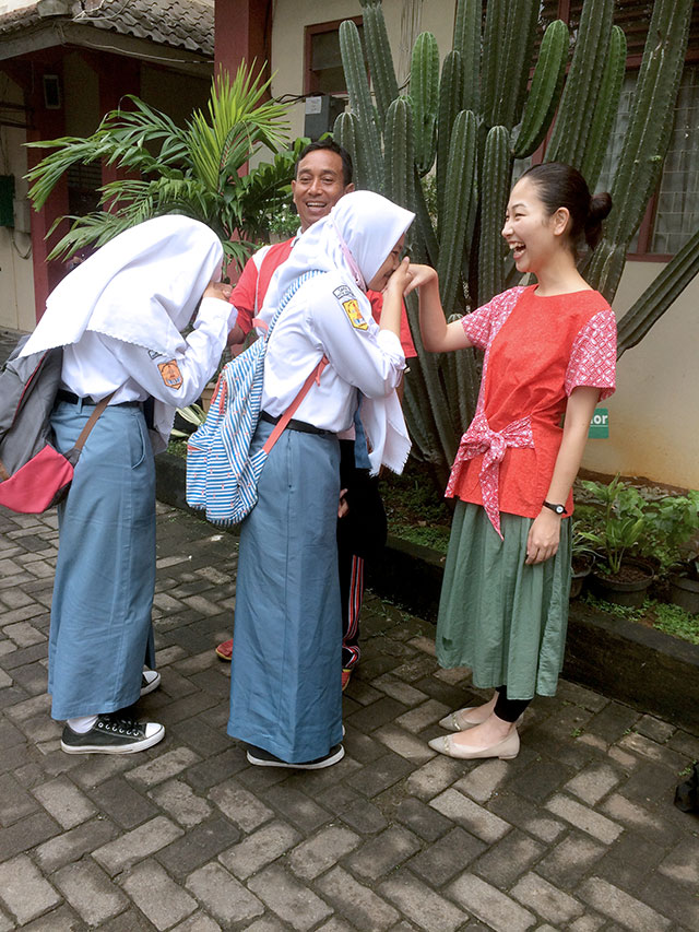 亀田さんに手の甲にキスして挨拶する女子生徒の写真。生徒も亀田さんも先生も笑顔の様子