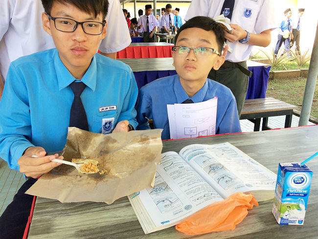 日本語パートナーズ マレーシア ジョホール州 男子生徒二人が本を広げながら食事をしている写真
