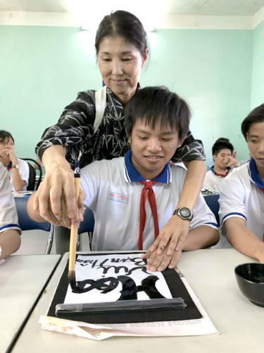 日本語パートナーズ ベトナム バリアブンタウ 生徒の手を取りながら一緒に文字を書いている写真
