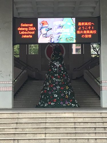 クリスマスツリーと「ようこそ！ふくい福井商業高校の皆様」と書かれた電光掲示板の写真