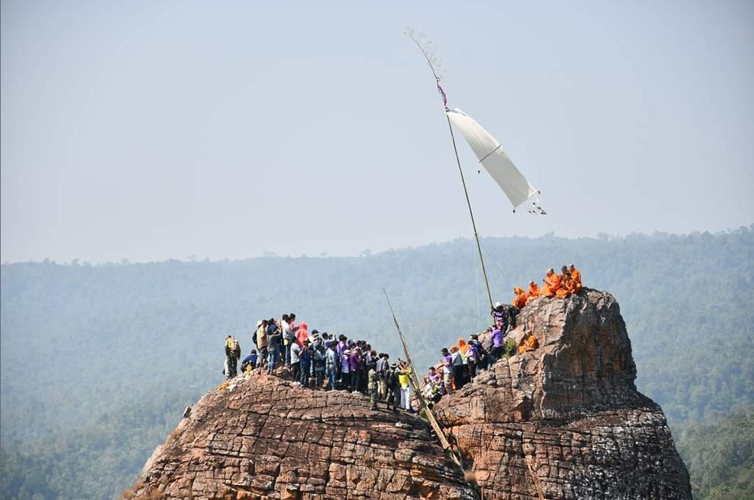 白い旗が掲げられた岩山の頂上の写真