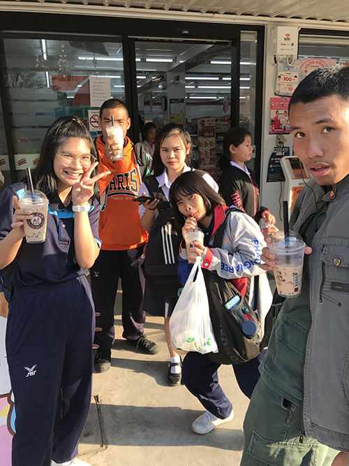 お店の前でコーヒーを飲む生徒たちの写真