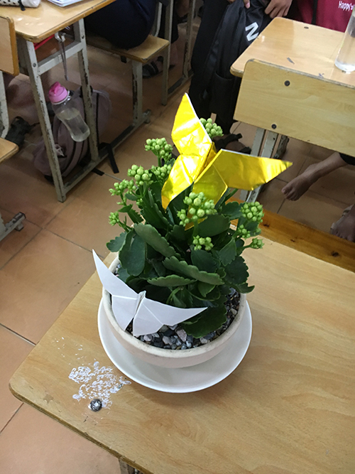 植木鉢の花に置かれた折り紙の写真