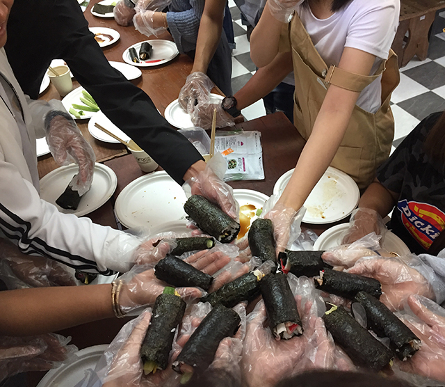 完成した巻き寿司を持った生徒たちの写真