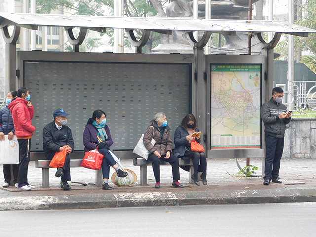 バス停でバスを待つ人たちの写真
