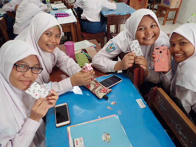 スマートフォンのケースを見せる女子生徒たちの写真
