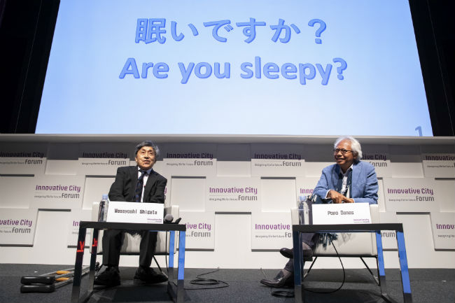 スライドを背にトークセッションを始める重田氏とポポ・ダネス氏の写真　スライドには「眠いですか？」とかかれている。