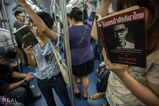 電車内で社会運動の本を読む人々の写真