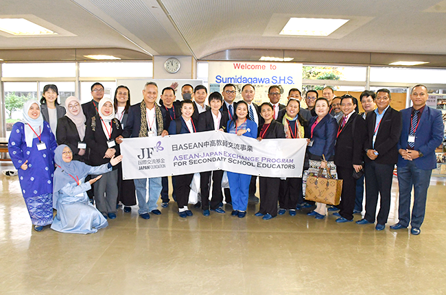 A commemorative photo of participants with several people in the center holding up a banner reading ASEAN-Japan Exchange Program