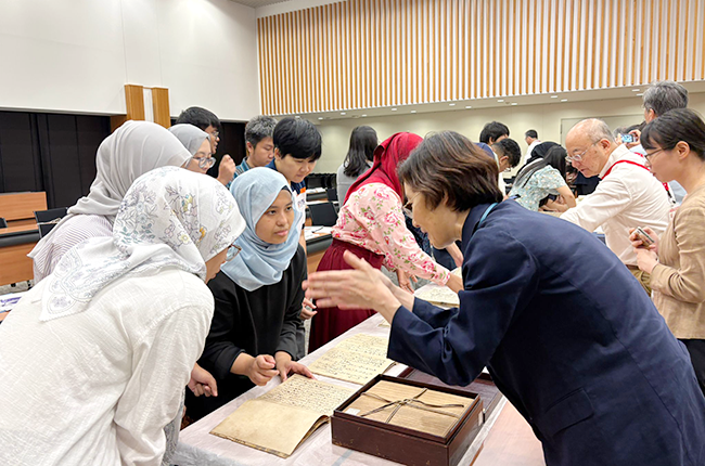 Participants listen to an explanation face-to-face in front of materials laid out on a long table
