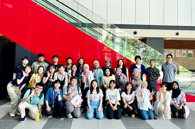 A group photo of about 30 participants with the bright red slope as a backdrop