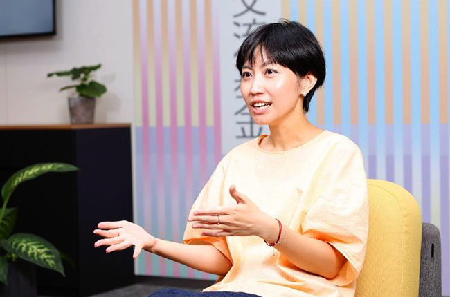 黄色い椅子に座り、両手を前に掲げて発言するルー・トゥアン・ウイエンさん