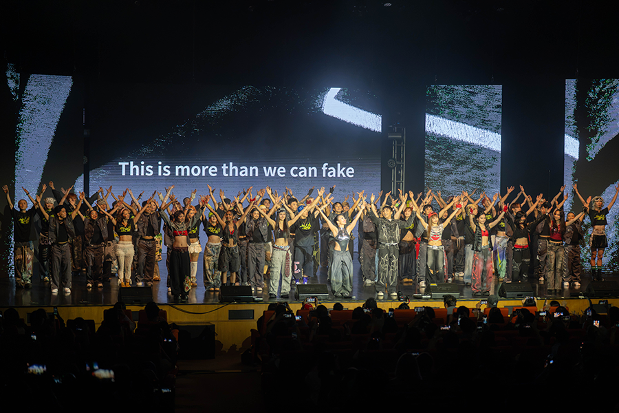 On stage, many men and women are raising both hands.
