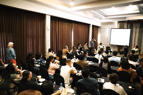 A lot of participants are gathered in a room where a screen has been set up.