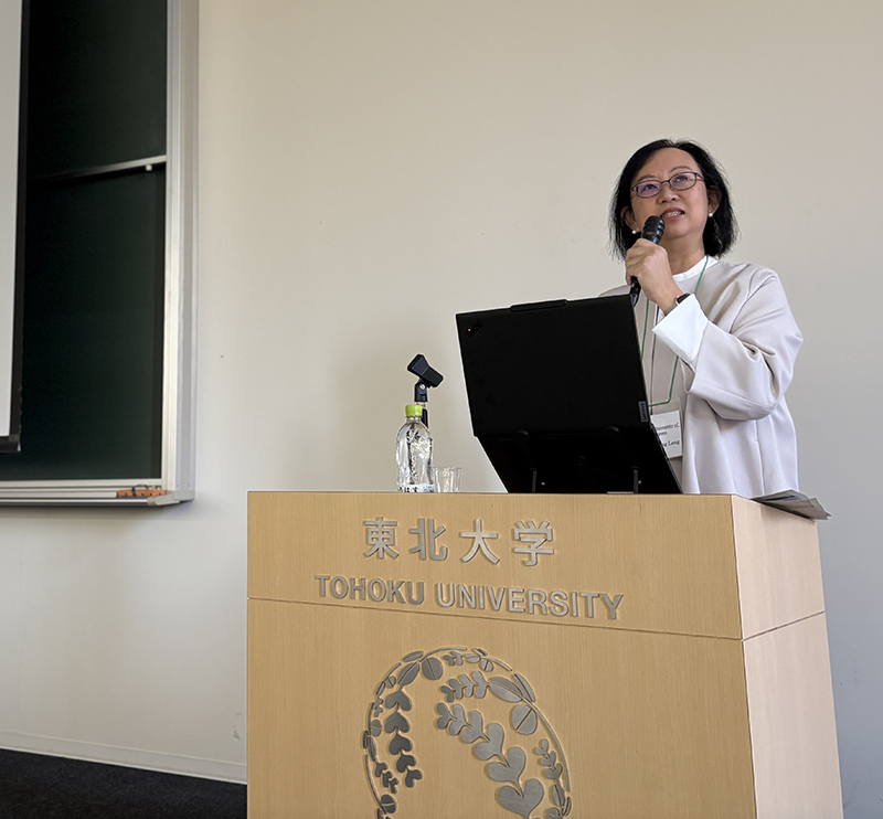 眼鏡をかけた女性が東北大学の壇上で講演している。