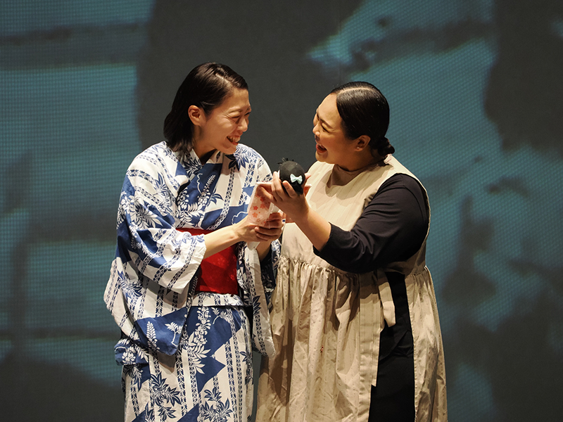 Two women are smiling and holding a doll.