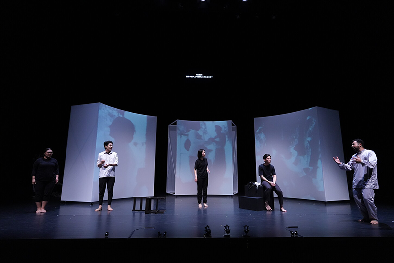 On the stage, the man on the right is saying something to the four people.
