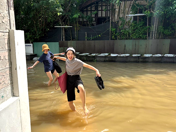 冠水した道路や水たまりの中を、靴を手に持って楽しそうに進む2人。
